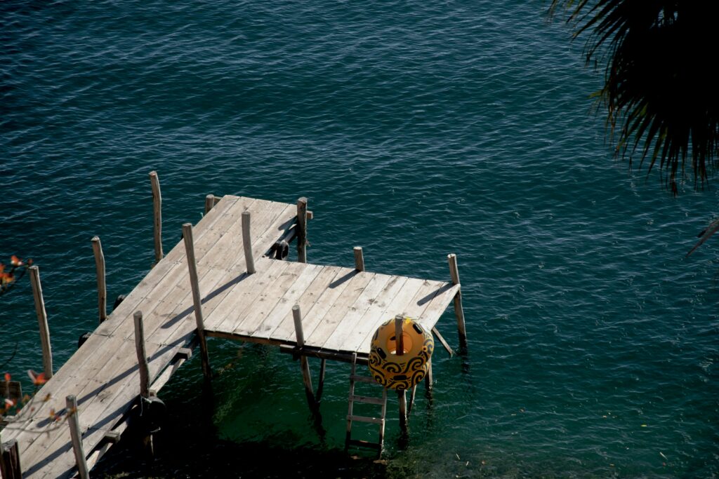 A tranquil dock on Lake Atitlán in Sololá, Guatemala, surrounded by clear blue water.